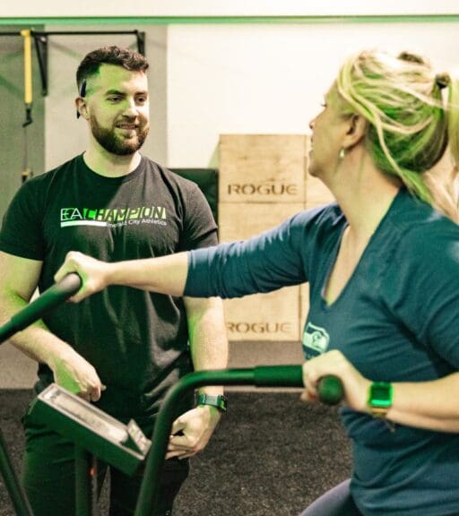 a gym member pedals on a stationary air bike during a personal training session with a certified trainer at emerald city athletics