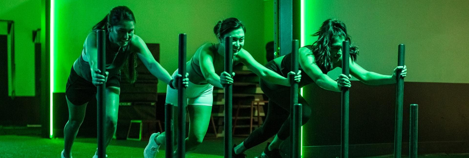 gym members push weighted sleds during a signature group fitness class at emerald city athletics gym near me